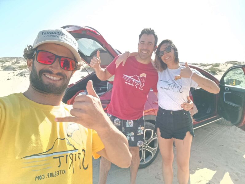 Andra e seus membros do acampamento de kitesurf posando na praia.