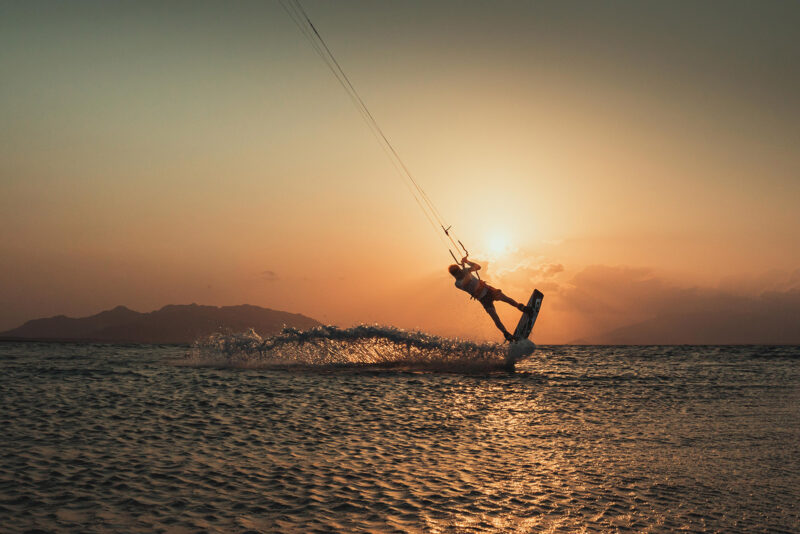 Kitesurfer rijden in vlak water en zonsondergang.