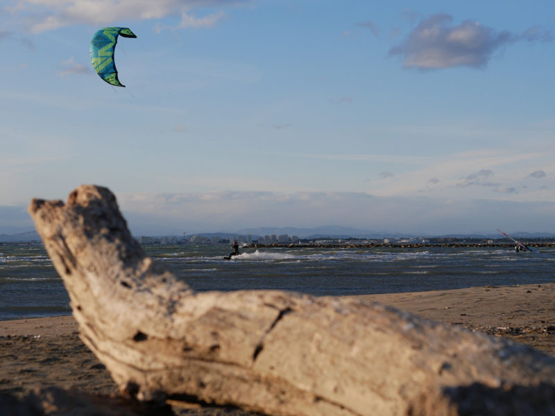 Kitesurfer pływa po płytkiej wodzie.