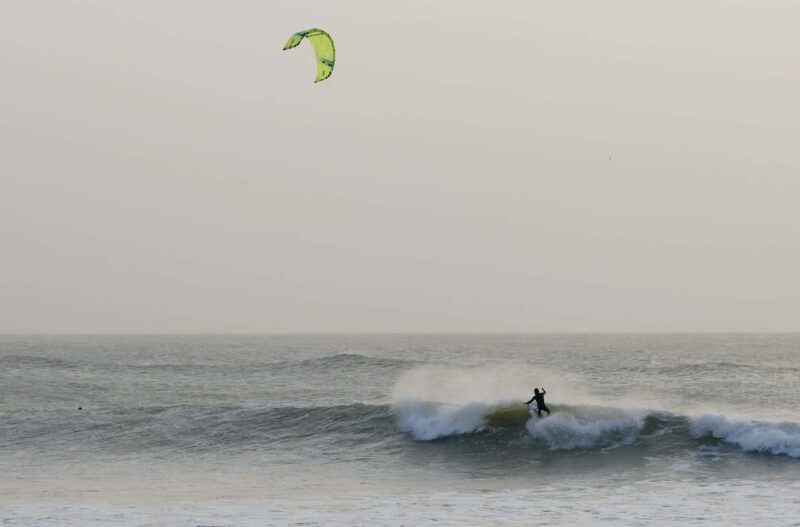 Surfistas e kiters andando em harmonia.