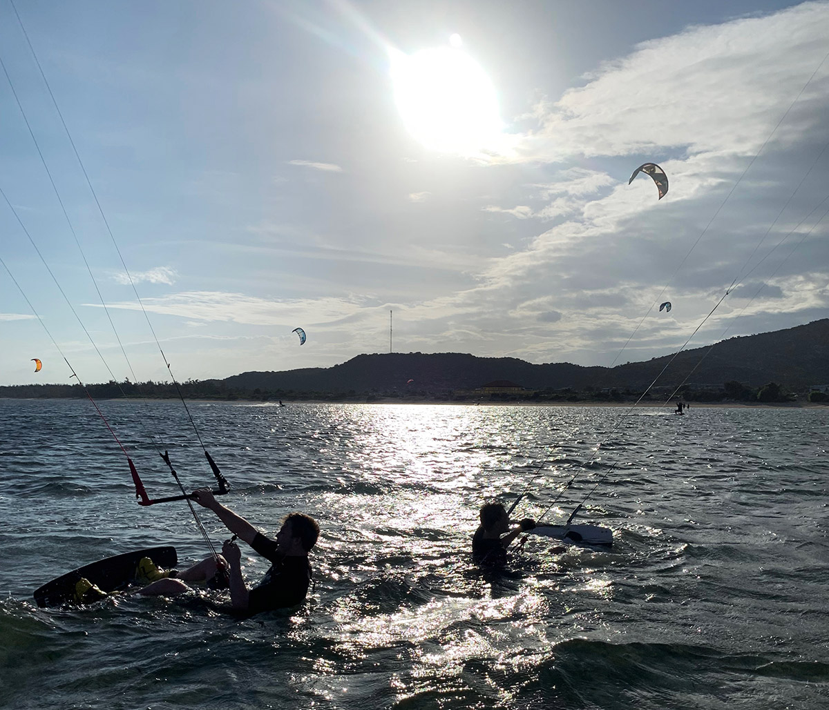Två kitesurfer i vattnet, ta en paus från ridning i My Hoa lagunen, Phan Rang.