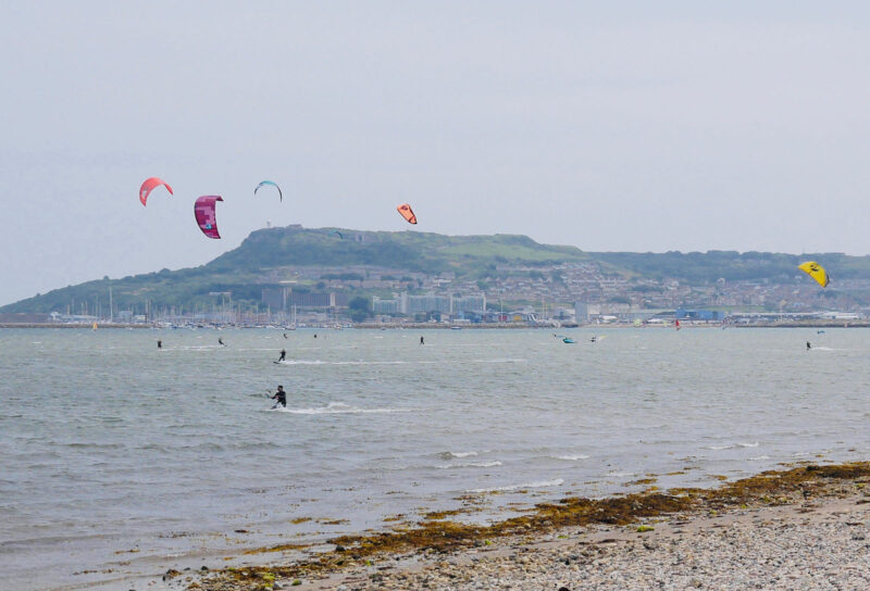 Portland backdrop with kitesurfers in the harbour.